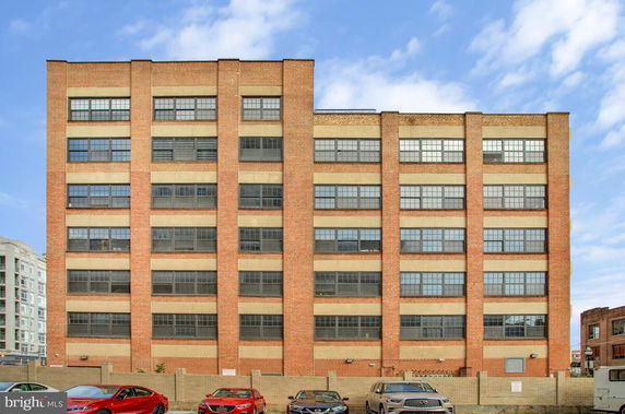 Front view of a multi-story brick building with large windows.