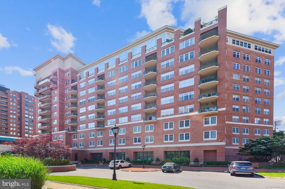 Front view of a multi-story brick apartment building with balconies.