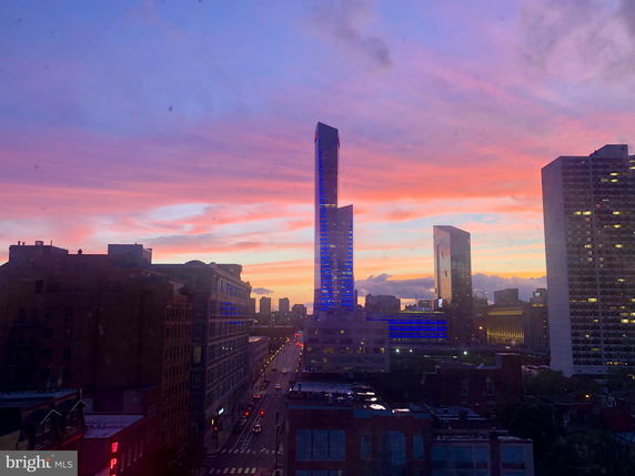 Panoramic view of a cityscape at sunset with tall buildings and a colorful sky.