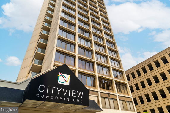 Front view of a tall condominium building with numerous windows.