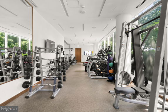Interior view of a gym with exercise equipment and large windows.