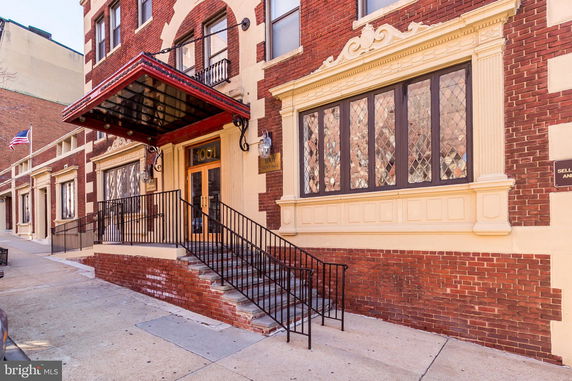 Front view of a brick building with decorative windows and an entrance canopy.