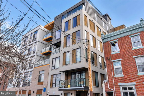 Front view of a modern multi-story apartment building with large windows and glass balconies.