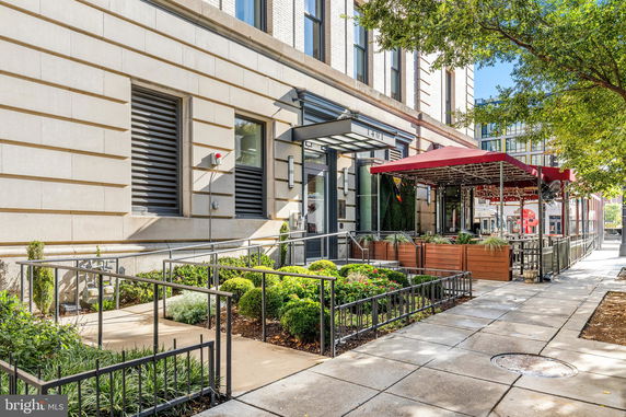Front view of a building with an entrance and sidewalk seating area.