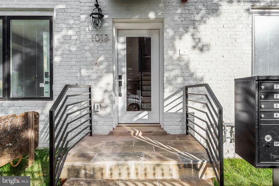 Front entrance of a brick house with a glass door and steps leading up.