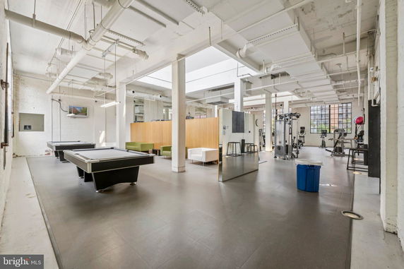 Interior of a recreation area featuring billiards tables and gym equipment.