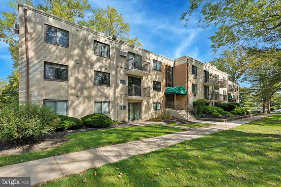 Front view of a multi-story apartment building with balconies and green awnings.