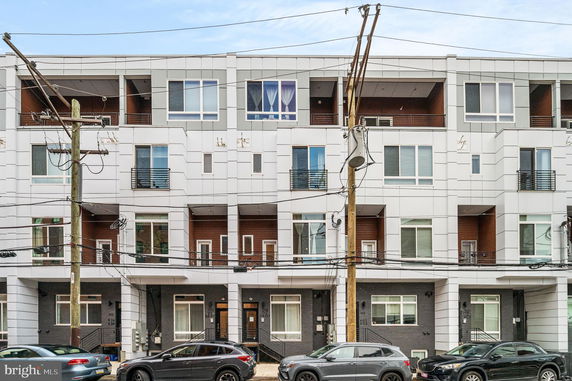 Front view of a modern multi-story building with balconies and large windows.
