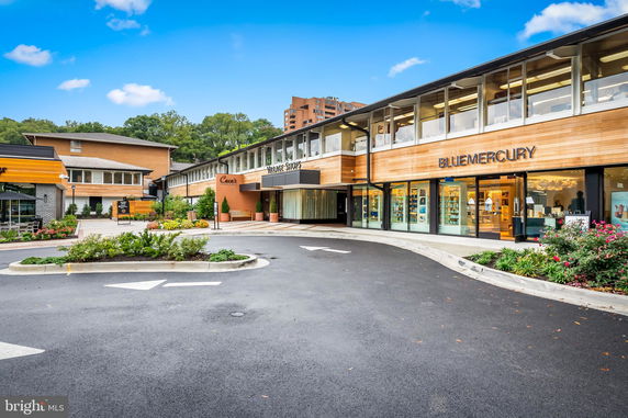 Front view of a shopping center with multiple shops including Bluemercury.