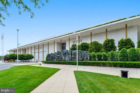 Front view of a large, modern building with columns and green landscaping.