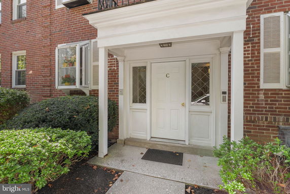 Front view of a brick building entrance with a white door and columns.