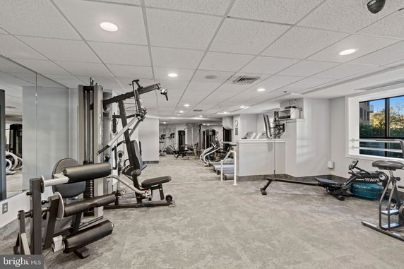 Indoor gym area with various exercise equipment and mirrors.