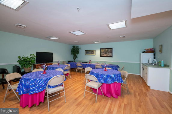 Indoor recreational area with tables and chairs, a TV, and small kitchenette.