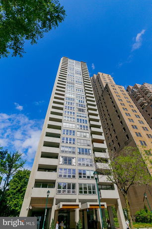 Front view of a tall apartment building with multiple windows and balconies.