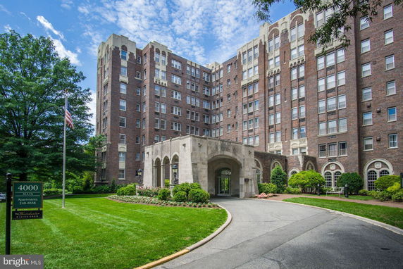 Front view of a multi-story apartment building with a central arched entrance.