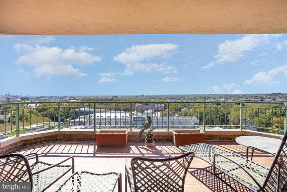 Wide angle view from a balcony overlooking a cityscape and greenery.
