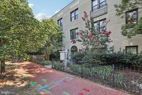Front view of a multi-story brick building with windows and a red brick pathway.