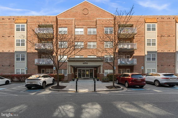 Front view of a multi-story brick building with balconies and a central entrance.
