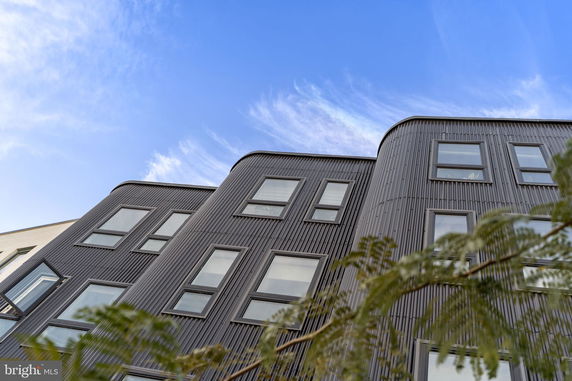 Front view of a modern multi-story building with a corrugated facade and multiple windows.