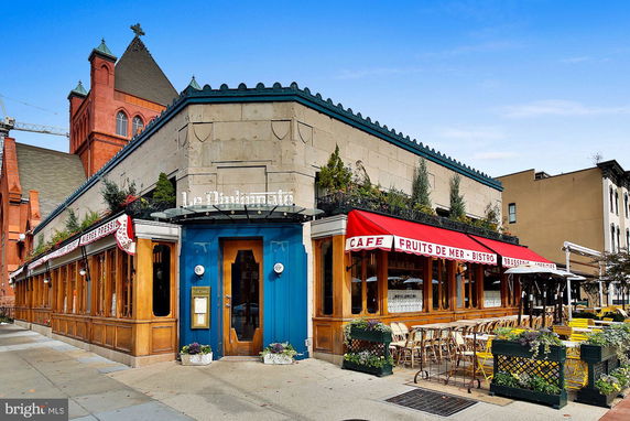 Front view of a cafe with a red canopy and outdoor seating area.