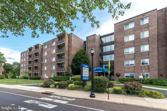 Front view of a multi-story brick apartment building with balconies.