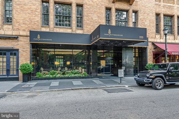 Front view of a brick building featuring a modern entrance with large glass windows and a black awning labeled 'PARC RITTENHOUSE.'