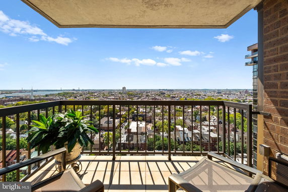 Balcony view overlooking a cityscape with numerous buildings and greenery.