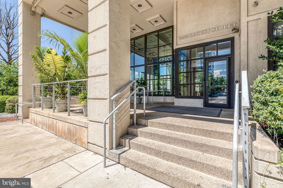Front view of a building entrance with glass doors and large columns.