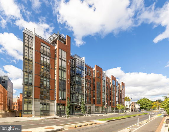 Front view of a modern multi-story building with large glass windows and brick accents.