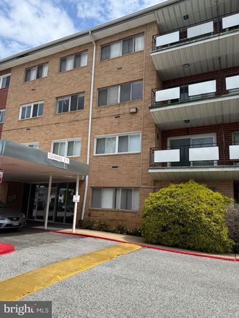Front view of a multi-story residential building with balconies and a covered entrance.
