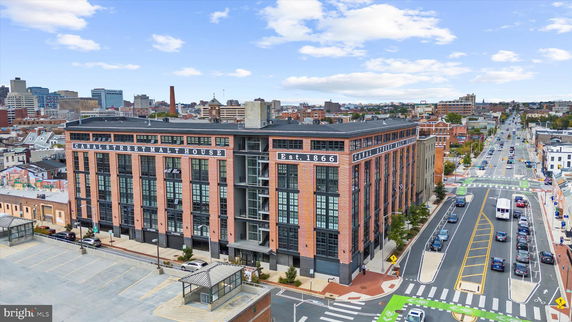 Front view of a large, historic brick building labeled 'Canal Street Malt House' with cityscape in the background.