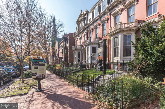 Front view of multi-story townhouses with ornate architectural details.