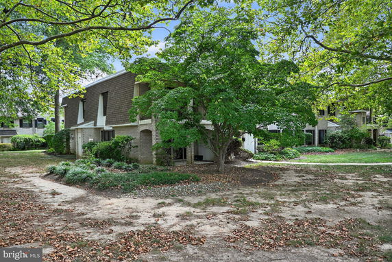 Front view of a two-story house with brick facade and trees in the foreground.