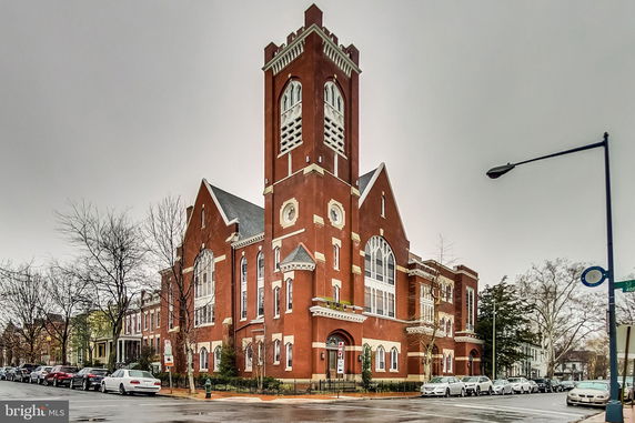 Front view of a large red brick building with a tall tower and arched windows.