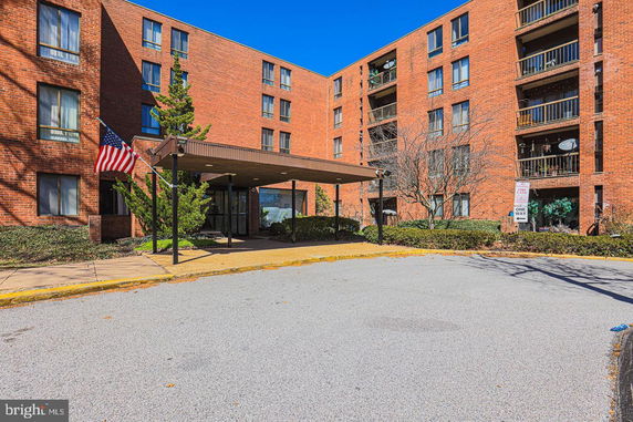 Front view of a brick apartment building with multiple floors and a covered entrance.