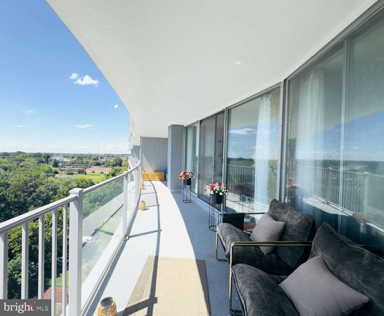 Balcony view with seating and glass railing overlooking surrounding area.