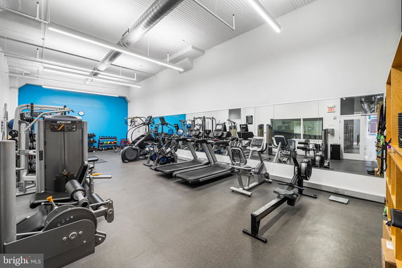 Interior view of a gym area with exercise equipment and mirrors.