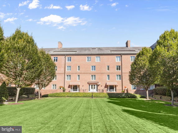 Front view of a multi-story brick building with a well-maintained lawn and trees.