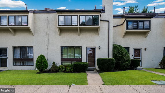 Front view of a two-story townhouse with large windows and a walkway.