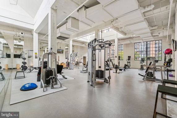 Spacious gym area with various exercise equipment and large windows.