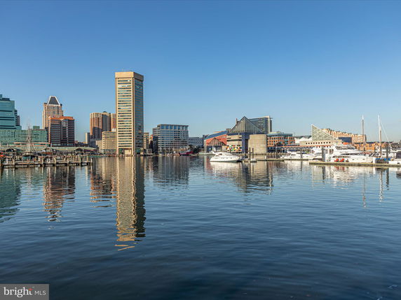 Wide angle view of a waterfront cityscape with tall buildings and yachts.
