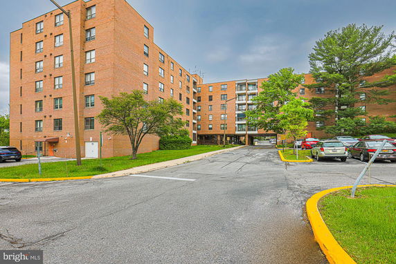Front view of a multi-story brick apartment building with parking area.