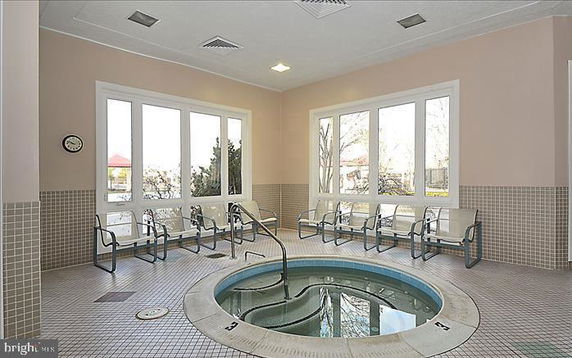 Indoor recreational area with a circular hot tub and seating.