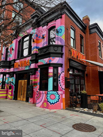 Front view of a colorful two-story building with brick and vibrant mural designs.