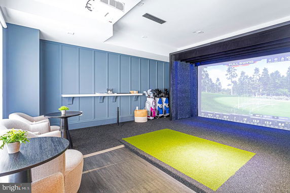 Indoor golf simulator room with seating area