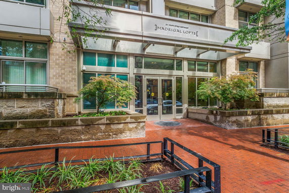 Front view of a modern building entrance with large glass doors and landscaping.