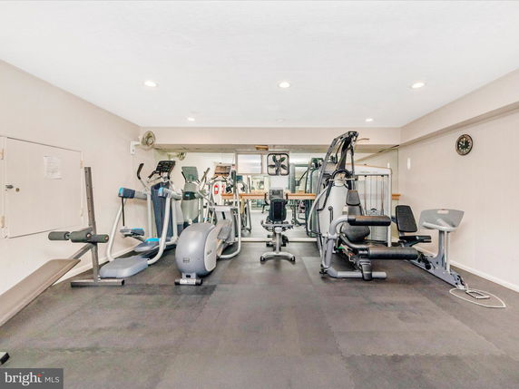 Room with gym equipment including treadmills, stationary bikes, and weight machines.