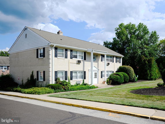 Front view of a two-story brick building with white columns and black shutters.