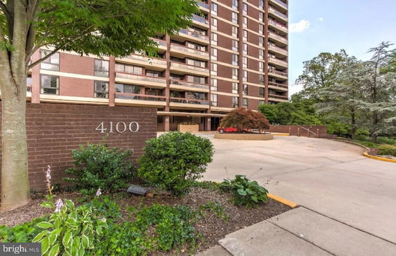 Front view of a multi-story apartment building with a driveway entrance.