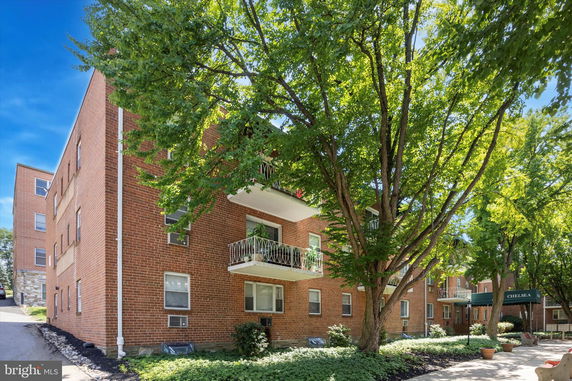 Front view of a multi-story brick apartment building with balconies.